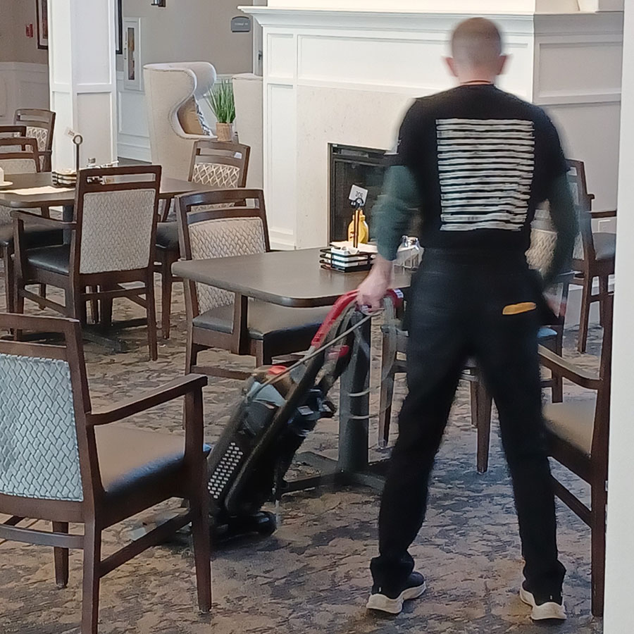 A worker tidying up the dining area in a senior community home.