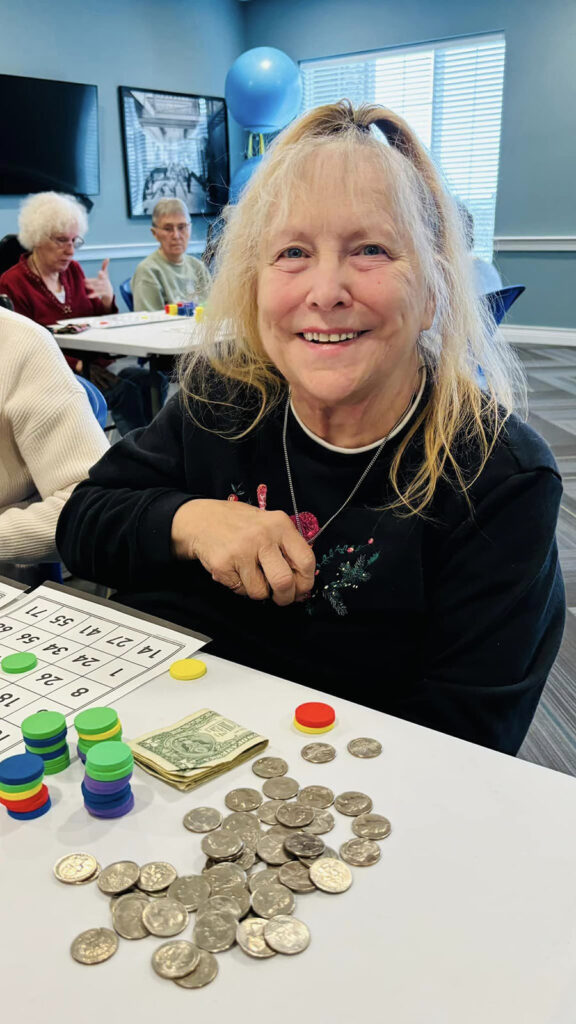 Woman with a joyful smile playing bingo at a senior living community, enjoying the game.