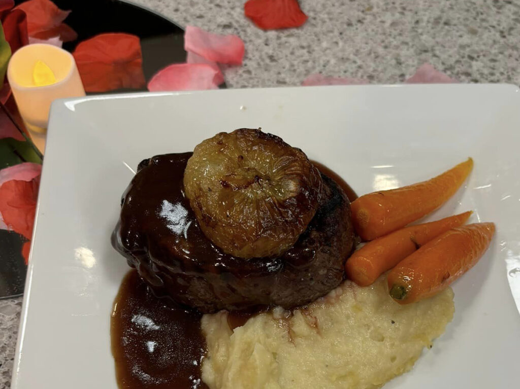 A delectable combination of a succulent steak, velvety mashed potatoes, and tender carrots, elegantly presented on a white plate.