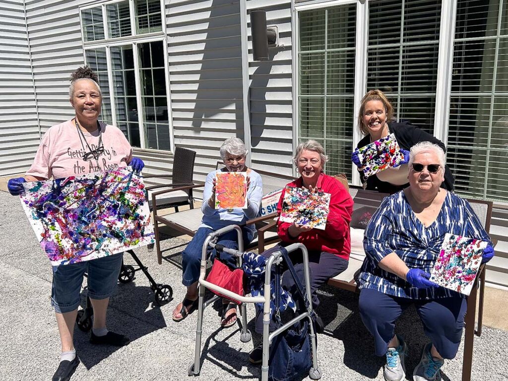 Five talented women proudly showcase their beautiful artwork outside the Vitalia Rockside senior living community.